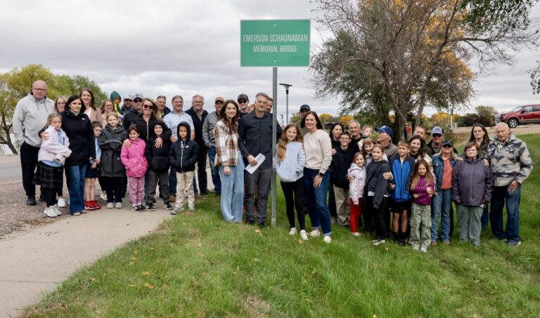 Aberdeen Mayor Travis Schaunaman along with family, friends and Edmunds County officials stand around a new sign at a bridge that crosses Mina Lake just east of Wakeside Bar & Grill along 133rd Street. The bridge was dedicated in honor of Emerson Schaunaman, the mayor's son, who died in August during a powered parachute crash. Photo courtesy of Travis Schaunaman